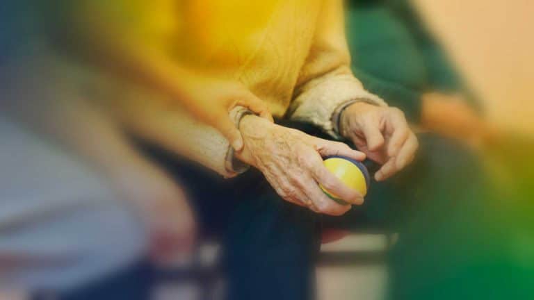 An adult care worker apprentice is holding the hand of an elderly person.