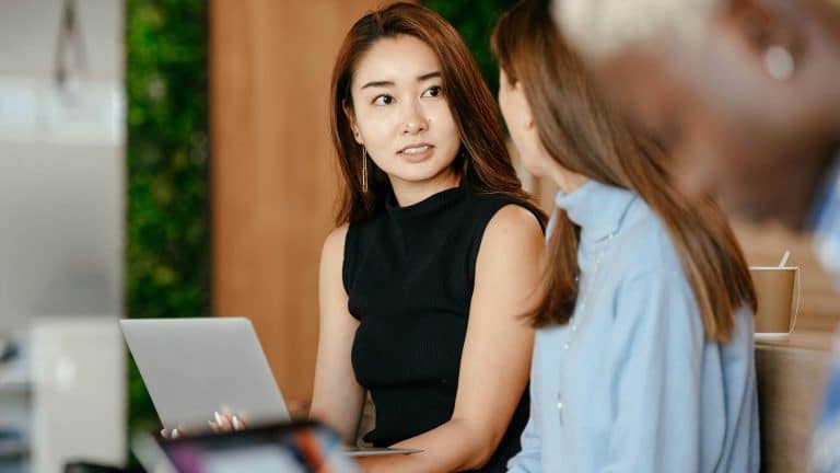 A female leader confidently talks to her staff after completing her leadership and management styles course.