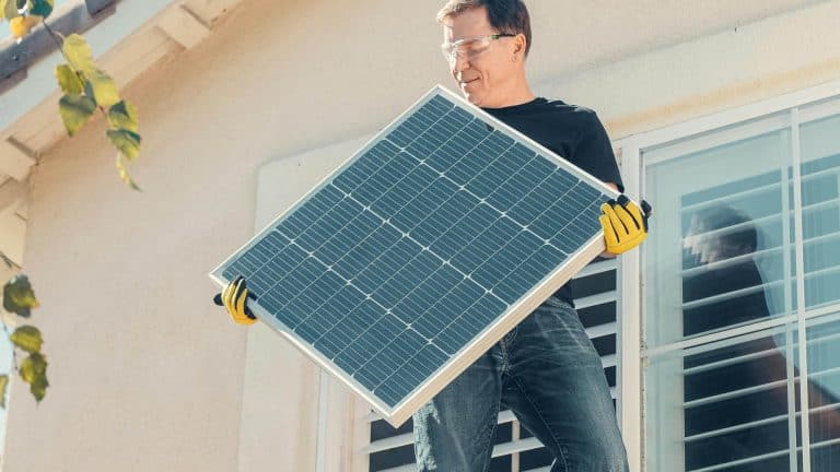 A man carrying a solar panel as part of the small solar photovoltaic systems course.