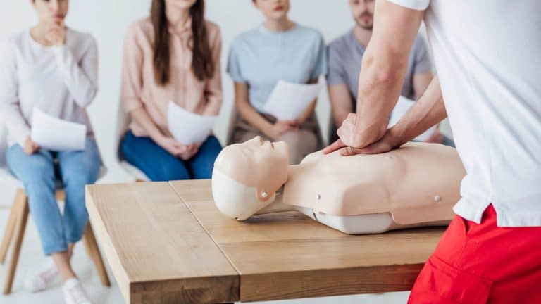 A trainer is demonstrating CPR as part of the FAA Award in First Aid at Work Course.